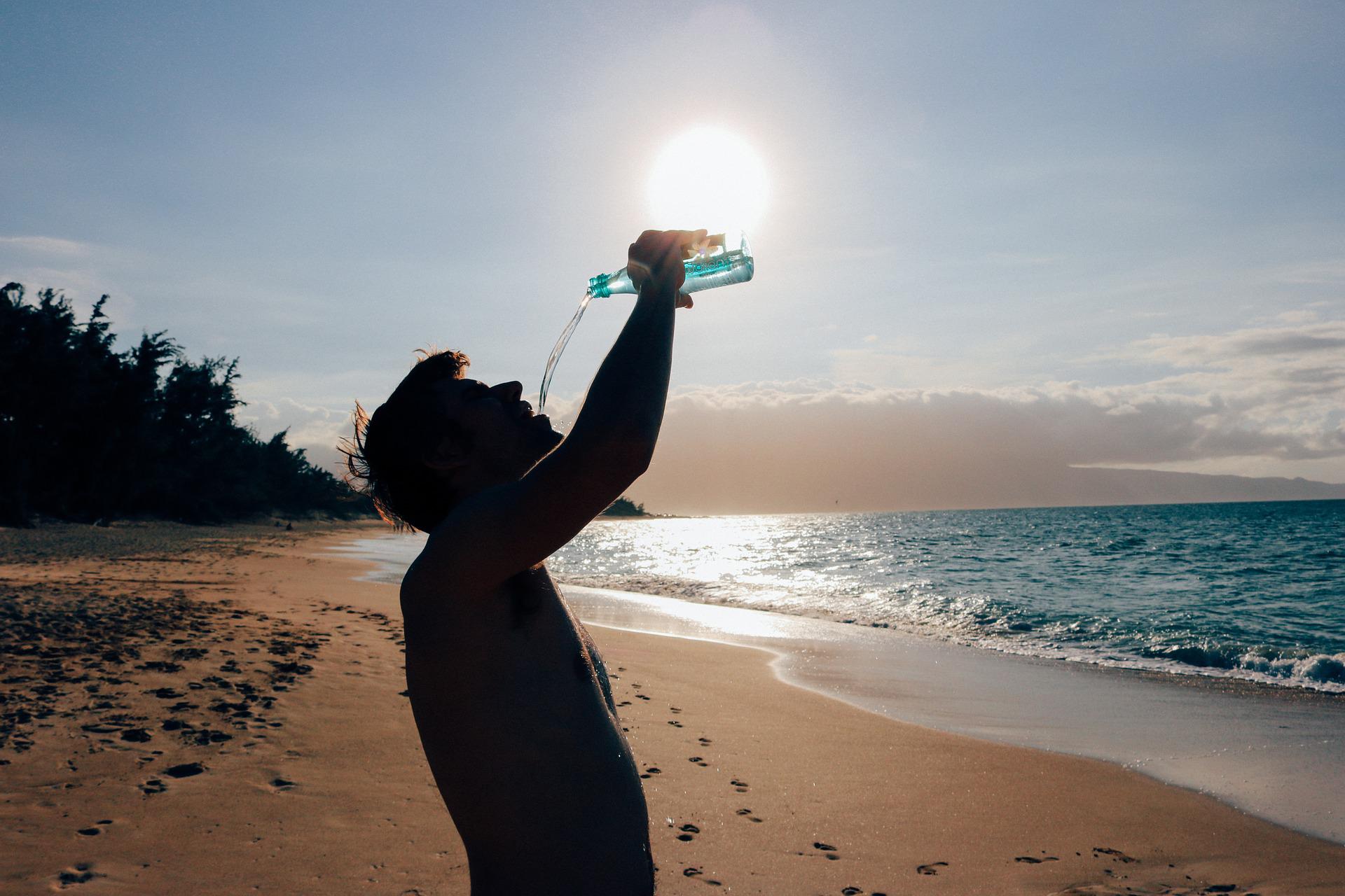 man drinking water on beach