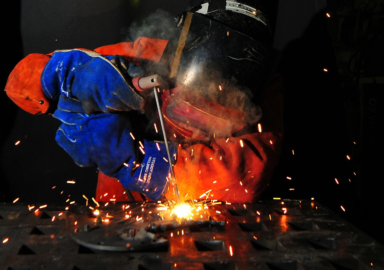welder with helmet and gloves welding - sparks flying